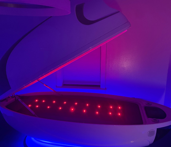 Cocoon wellness pod open with red light therapy inside, glowing in a spa room designed for relaxation, detox, and full-body recovery.