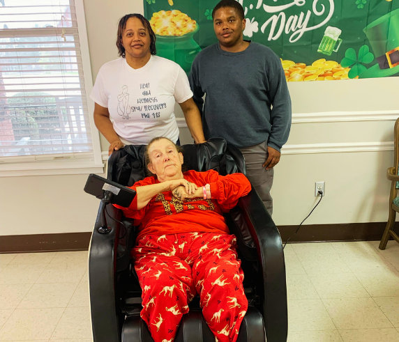 Client relaxing in a full-body massage chair with Heat and Wellness Spa staff in Ripley, MS, highlighting therapeutic massage chair services that help reduce muscle tension, relieve stress, improve circulation, and support overall wellness.
