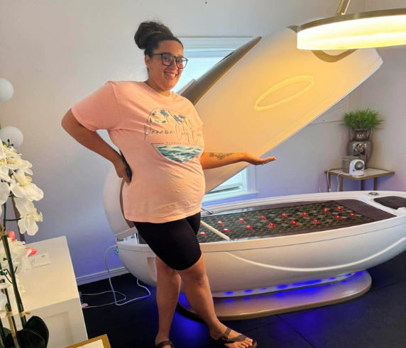 Client standing beside the Cocoon Wellness Pod at Heat and Wellness Spa in Ripley, MS, showcasing an infrared wellness treatment designed to promote deep relaxation, improve circulation, support natural detoxification, and relieve muscle tension.