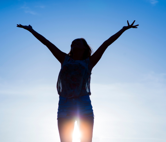 Silhouette of a woman with her arms raised toward the sky, representing mental clarity, stress relief, emotional wellness, and renewed energy through Brain Therapy at Heat and Wellness Spa in Ripley, MS.